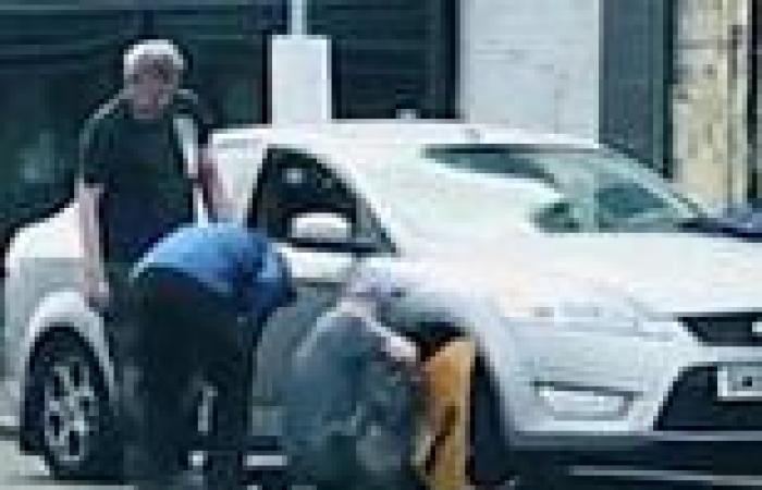 Moment three men remove WHEEL CLAMP using angle grinder in busy high street