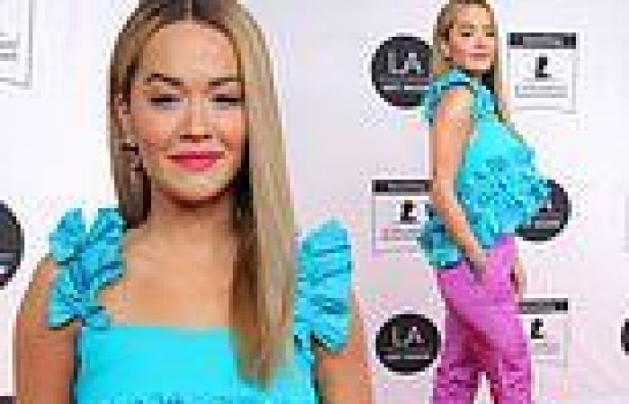 Rita Ora looks bold as she pairs a ruffled turquoise top with magenta trousers ...