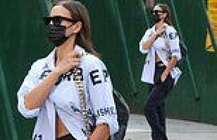 Irina Shayk teases her taut midriff in a partially unbuttoned shirt as she ...