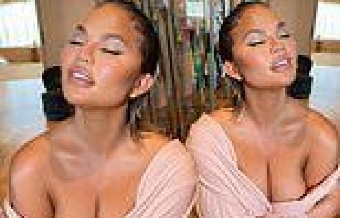 Chrissy Teigen puts on a busty display in a VERY low-cut pink top