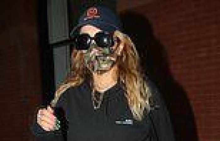 Rita Ora cuts a low-key figure in a black tracksuit, cap and shades
