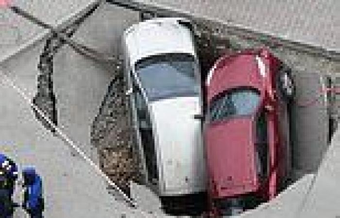 Swallowed by the road: Two cars trapped after huge sinkhole opens up on Russian ...