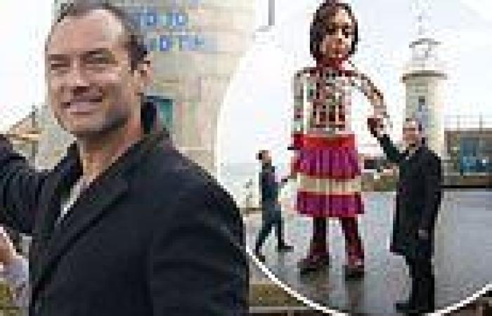 Jude Law takes puppet Little Amal by the hand as he walks along Folkstone beach