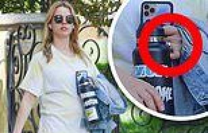 Mia Goth covers her baby bump with a jean jacket as she flashes an engagement ...