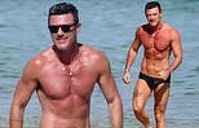Luke Evans shows off his RIPPED physique at the beach... as he gets a kiss from ...