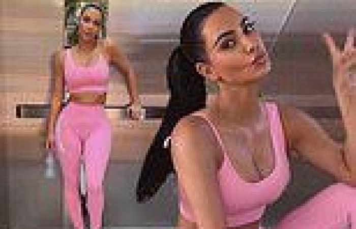 Kim Kardashian flashes a peace sign while in a pink bra top and leggings
