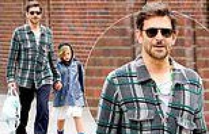 Bradley Cooper wears a beaded necklace that reads MAGIC as he holds hands with ... trends now