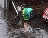 Uber Eats cyclist takes off his shoes to wade through flooded street to deliver ...