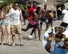 Tourists breeze past Hattian migrants playing soccer on a Colombia beach  